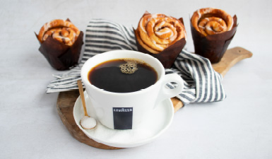 A cup of Lavazza coffee with baked goods on a table