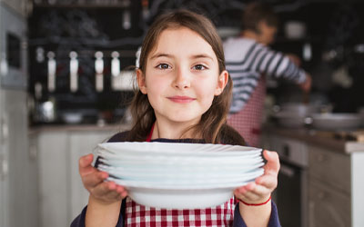 Little girl holding a stack of white bowls